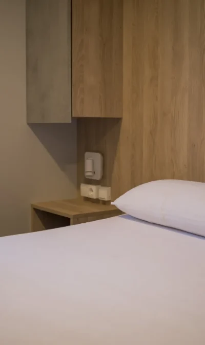 Habitación moderna con cama blanca y detalles en madera.