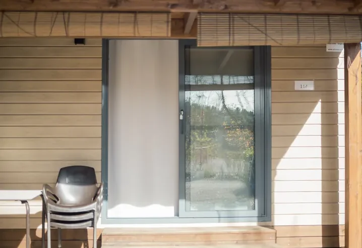 Puerta de entrada a cabaña moderna con sillón exterior.