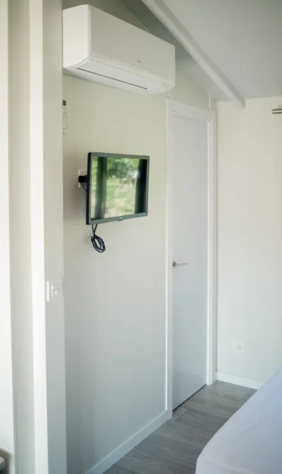 Aire acondicionado y televisor en pared de habitación moderna.