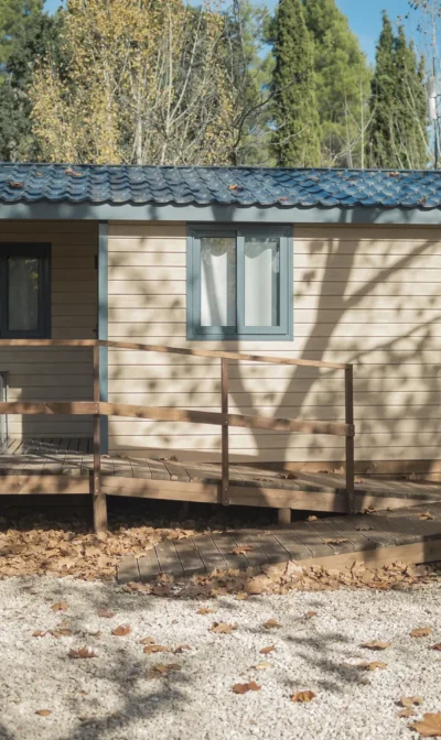 Cabaña de madera con terraza y hojas caídas alrededor.