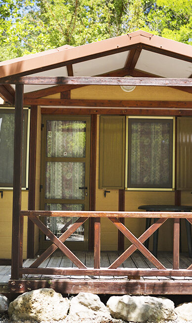 Cabaña con terraza en un entorno natural y árboles.